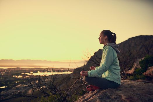 Meditation with a view. Full length shot of a sporty young woman meditating outdoors.