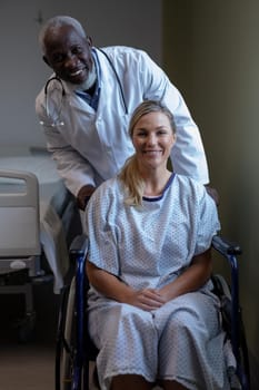 Portrait of diverse male doctor and female patient sitting on wheelchair smiling to camera. medicine, health and healthcare services.