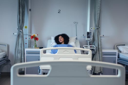 Thoughtful african american female patient lying in hospital bed looking to side