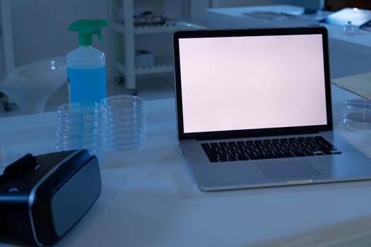Laptop computer with illuminated screen at workstation in medical laboratory