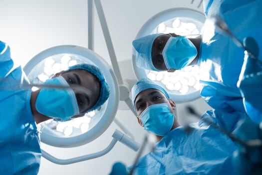 Diverse surgeons wearing face masks and protective clothing in operating theatre