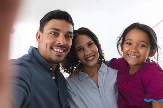Happy hispanic couple and daughter taking selfie smiling to camera