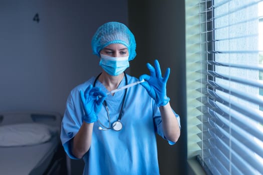 Caucasian female doctor in hospital wearing face mask and surgical gloves holding swab test
