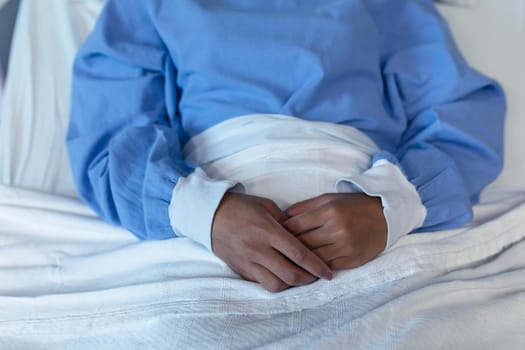 Midsection of african american female patient lying in hospital bed