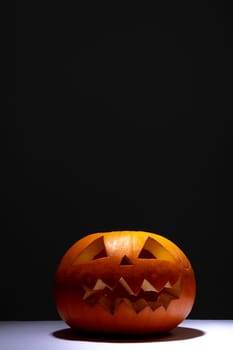 Composition of scary halloween carved orange pumpkin on black background