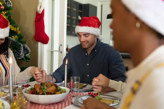 Caucasian man praying with friends at christmas table at home