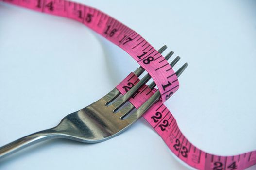 Fork tied with measuring tape. Weight loss and fitness concept