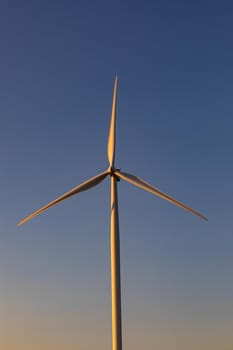 Close up of wind turbine in countryside landscape with cloudless sky