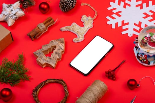 Composition of smartphone with copy space and christmas decorations on red background