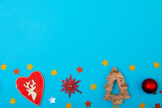 Composition of christmas decorations with silver bauble, heart and stars on blue background