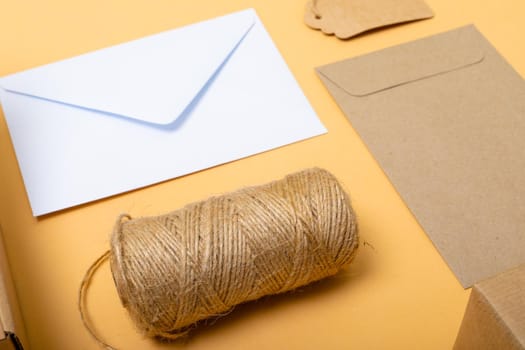 Composition of rope, envelopes and gift tag on yellow background