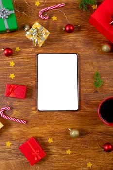 Composition of tablet with copy space and christmas decorations on wooden background