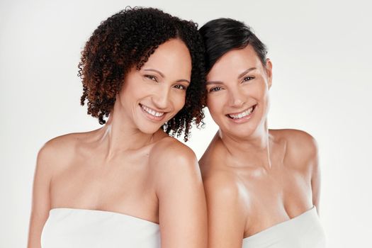 Cropped portrait of two beautiful mature women posing against a grey background in studio.