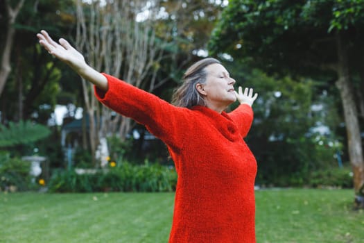 Happy senior caucasian woman with arms outstretched in garden
