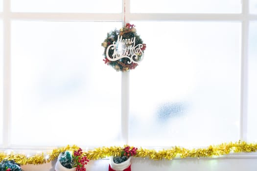 Composition of merry christmas sign in window, with christmas stockings