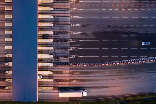 Car traffic transportation on multiple lanes highway road and toll collection gate, drone aerial top view at Night. Commuter transport, city life concept.A2 Poland Lodz