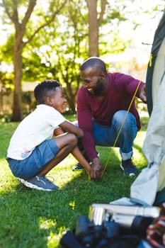 African american father with son having fun and pitching tent in garden. family spending time at home.
