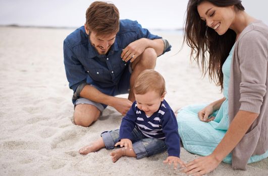 Nurturing his curiosity about nature. Cropped shot of a young couple and their baby boy sitting on the beach.