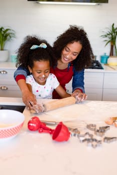 Happy african american mother and daughter baking together in kitchen