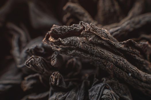Extreme macro Black loose leaf tea as a background. Texture of dry black tea leaves in shallow depth of field. Dark background. macro mode. black leaf tea closeup