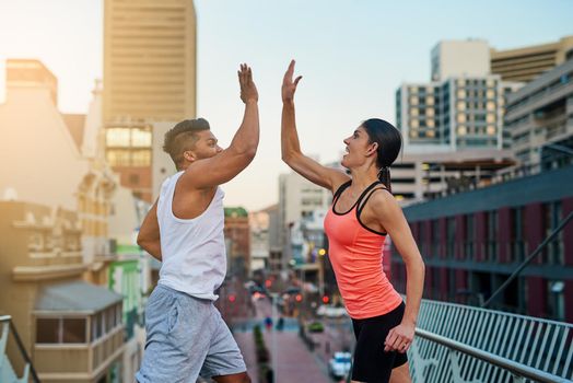 We did it. Shot of a young couple giving each other high five during their workout.