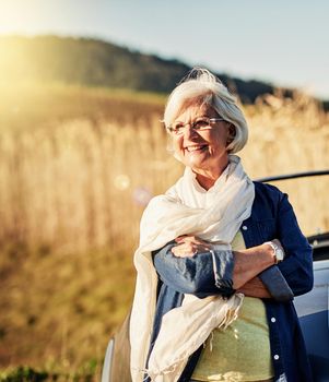 Miss Daisy drives herself these days. Shot of a senior woman posing next to a convertible while out on a roadtrip.