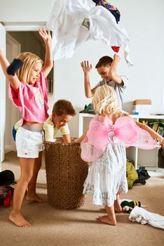 Its raining clothes. Shot of little siblings throwing laundry in the air at home.