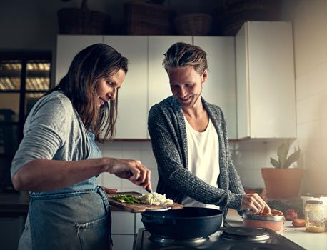 Shot of a mother and her adult son cooking together in their kitchen at home.