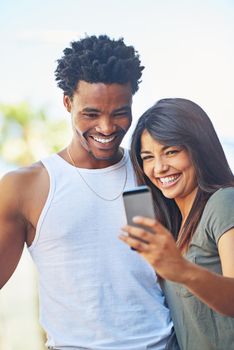 Couple profile pic. Shot of a happy young couple using a mobile phone together.