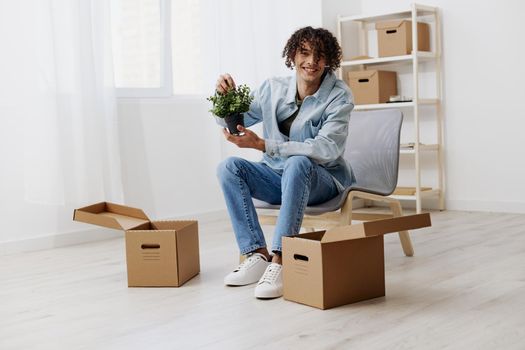 guy with curly hair cardboard boxes in the room unpacking Lifestyle. High quality photo