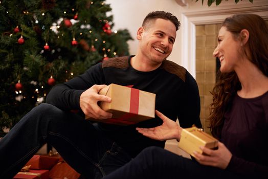 The best gift around the tree is love. A happy young couple opening presents on Christmas day.
