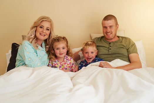 Family is not an important thing - its everything. Portrait of a happy family relaxing in bed together at home.