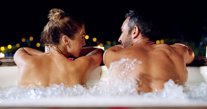 Were back in the swing of things. Rearview shot of an affectionate mature couple relaxing in a hot tub together at night.