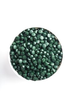 Spirulina tablets in a white cup on a white background