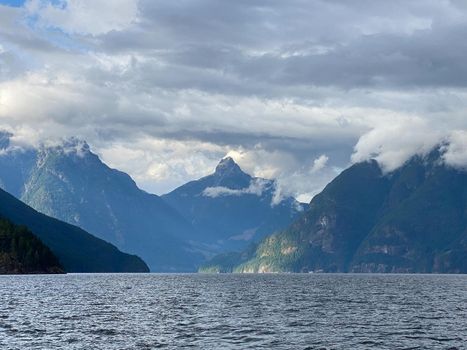 Jervis Inlet north in British Columbia, surrounded by high, rugged peaks of the Coast Mountains and beautiful water clouds in the sky