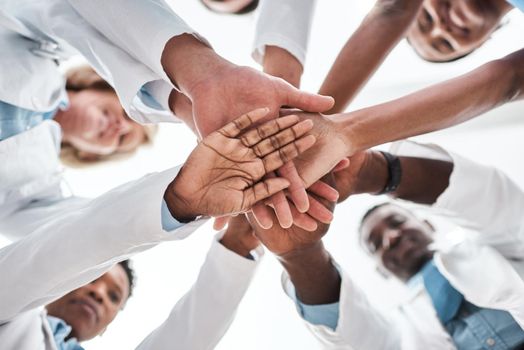 Team-based care is essential for meeting value-based care goals. Closeup shot of a group of medical practitioners joining their hands together in a huddle.
