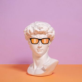 A statue of a bust of Roman David in sunglasses and a symbol of bitcoin.