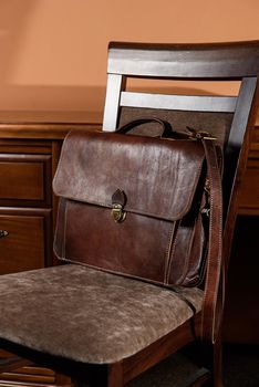 brown leather briefcase with antique and retro look for man on a chair. Hotel room photo