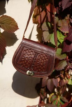 small brown women's leather bag with a carved pattern. street photo