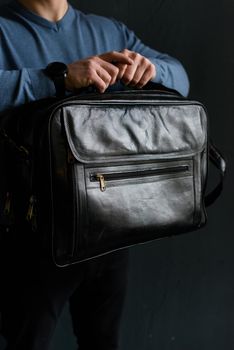 Man holding black leather travel bag. Soft light