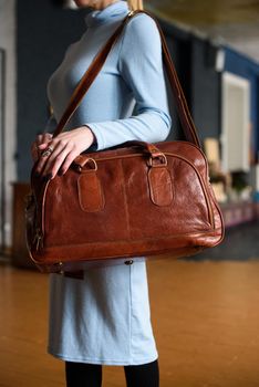 close-up photo of orange leather travel bag on womans shoulder