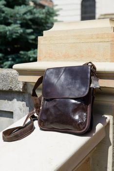 Outdoor photo of a brown leather Messenger bag.