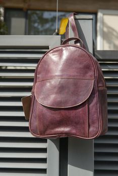 burgundy leather backpack on the metal fence