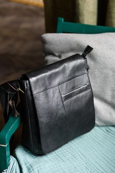 close-up photo of black messanger leather bag on a chair