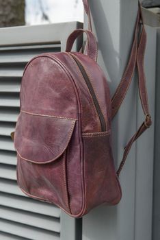 burgundy leather backpack on the metal fence