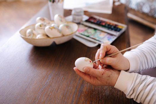 Woman painting a water colors on fantasy chicken eggs for Easter egg festival. Female drawing little yellow chick. The symbolic of Spring. Easter concept