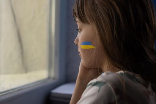 Little girl with Ukrainian flag ribbon praying. Symbol of peace and pray for Ukraine.