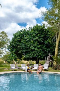 couple men and woman by the pool on a luxury safary,South Africa, luxury safari lodge in the bush