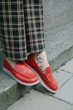 woman's legs in chequered trousers and red shoes