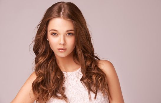 Glam hair and natural beauty. Gorgeous young brunette against a pink background.